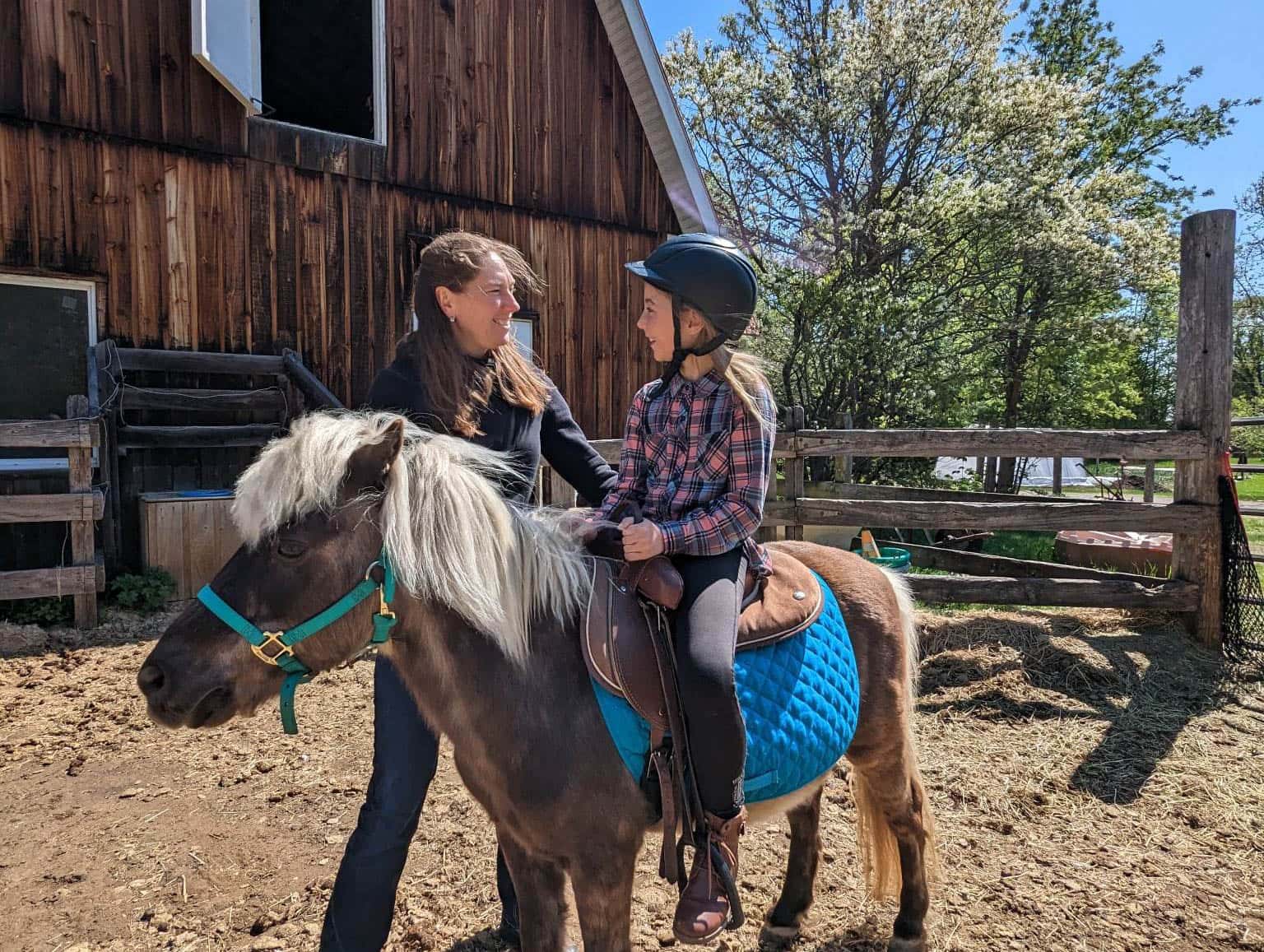 Les trois éléments de base de la zoothérapie : un client un animal et un intervenant. (Enfant sur un poney accompagné d'une éducatrice).